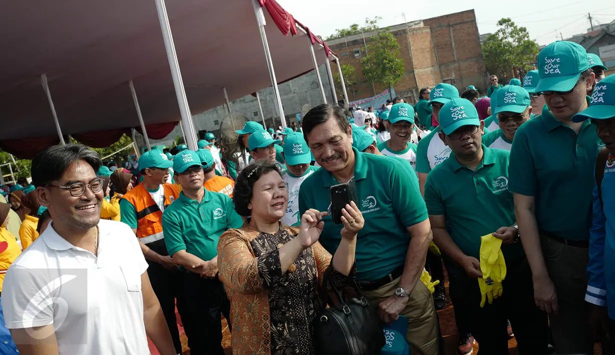 Menteri Koordinator Bidang Kemaritiman Luhut Binsar Panjaitan berfoto bersama seorang warga saat menggelar gerakan aksi bersih di kawasan pesisir Cilincing, Jakarta Utara, Sabtu (6/4). (Liputan6.com/Immanuel Antonius)