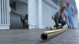 Seorang pekerja mengukur pipa untuk perbaikan pintu stadion yang rusak di Stadion Utama Gelora Bung Karno, Kamis (22/2/2018). Empat pintu stadion yang mengalami kerusakan adalah pintu bernomor 5B, 7B, 9, dan 10. (Bola.com/Nick Hanoatubun)
