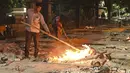 Staf memeriksa tumpukan kayu yang terbakar dari korban Covid-19 di Krematorium Nigambodh Ghat, New Delhi, Kamis (22/4/2021). India sekarang menjadi negara terparah kedua di dunia setelah AS, dengan kasus baru lebih dari 200.000 infeksi baru setiap hari selama sepekan terakhir. (Sajjad HUSSAIN/AFP)