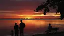 Orang-orang menikmati matahari terbenam di danau Chiemsee di Chieming, Jerman, Selasa, (25/8/2020).  Danau yang terletak di dekat kota Rosenheim ini sering diberi julukan "Laut Bayern'. (AP Photo / Matthias Schrader)