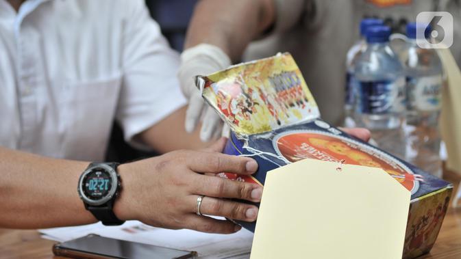 Polisi menunjukkan barang bukti kaleng biskuit di Ditnarkoba Polda Metro Jaya, Jakarta, Senin (7/10/2019). Tersangka MH menyelundupkan sabu dengan modus diselipkan ke dalam kaleng biskuit dan menyamarkan 12 cangklog atau alat isap yang di dalam air kemasan. (merdeka.com/Iqbal S. Nugroho)