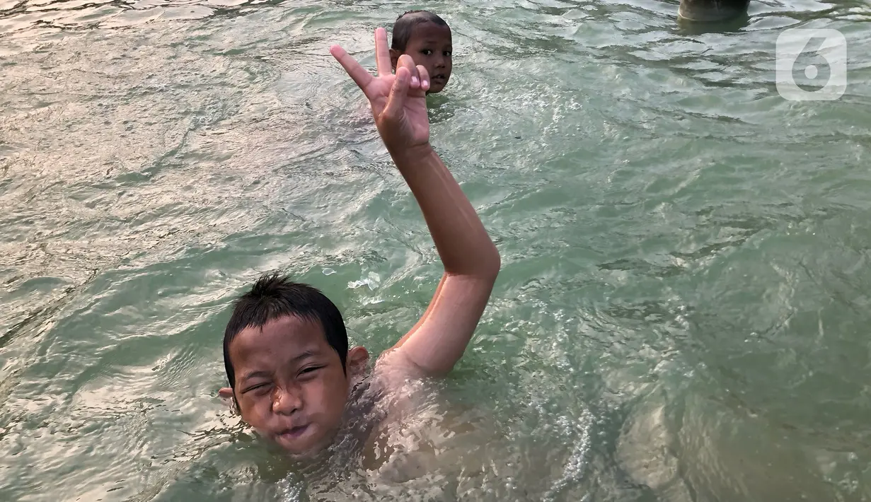 Keseruan anak-anak berenang di kolam penghias taman Pasar Baru di Jakarta, Rabu (2/9/2020). Meskipun terdapat larangan, namun sejumlah anak tetap nekat berenang di kolam tersebut sehingga mengganggu ketertiban umum. (Liputan6.com/Immanuel Antonius)