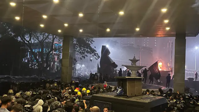 Massa mahasiswa bertahan di tengah guyuran hujan deras saat aksi unjuk rasa di Polda Metro Jaya.