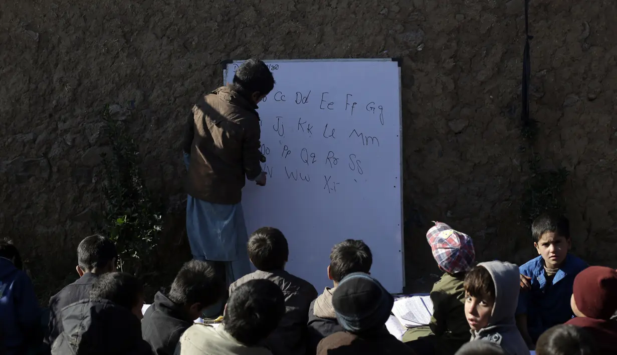 Anak-anak sekolah pengungsi Afghanistan menghadiri kelas di sekolah darurat di pinggiran Islamabad, Pakistan, Rabu (29/12/2021). (AP Photo/Rahmat Gul)