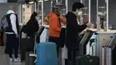 Pelancong untuk Amerika Serikat menunjukkan dokumen mereka di meja check-in di bandara Charles de Gaulle, utara Paris, Senin (8/11/2021).  Pencabutan pembatasan perjalanan memungkinkan wisatawan untuk melakukan perjalanan yang lama tertunda. (AP Photo/Christophe Ena)