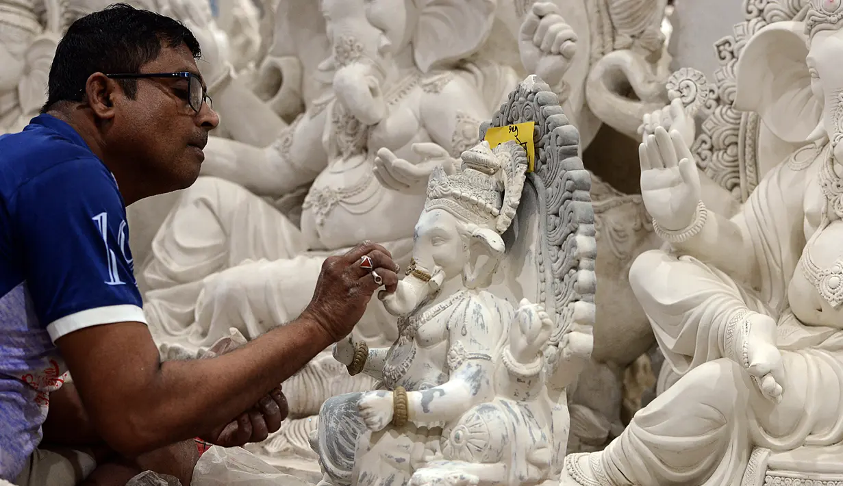 Seorang perajin mengerjakan pembuatan patung Dewa Ganesha di sebuah bengkel di Mumbai, India, 24 Agustus 2021. Pembuatan patung dewa Hindu berkepala gajah tersebut dilakukan jelang Festival Ganesh Chaturthi. (SUJIT JAISWAL/AFP)