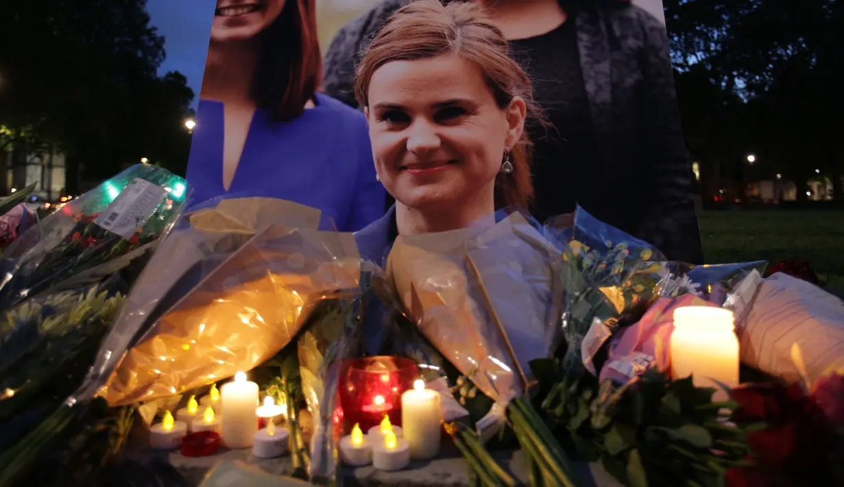 Karangan bunga dan lilin diletakkan di dekat foto anggota parlemen Inggris, Helen Joanne Cox, atau biasa dipanggil Jo Cox di alun-alun Parlemen, London, Kamis (16/6). Jo Cox tewas akibat ditembak seorang pria di jalan. (Daniel Leal-Olivas /AFP)