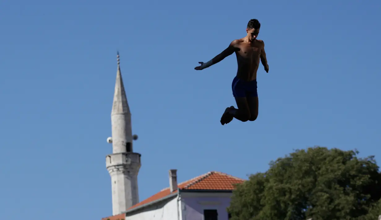 Seorang peserta melompat dari jembatan saat mengikuti acara kompetisi menyelam tradisional ke 451 di Mostar, Bosnia, Minggu (30/7). Total 41 peserta dari Bosnia dan negara-negara tetangga mengikuti kompetisi menyelam tahunan tersebut (AP Photo/Amel Emric)