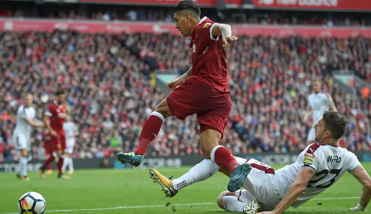 Aksi pemain Liverpool, Roberto Firmino melompat melewati adangan pemain Burnley, Stephen Ward (kanan) pada laga Premier League di Anfield Stadium, Liverpool (16/9/2017). Liverpool bermain imbang 1-1. (AFP/Paul Ellis)