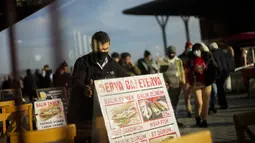 Seorang pramusaji meletakkan papan menu di luar restoran lokal di terminal feri Karakoy di Istanbul, Turki, Senin (3/1/2022). Inflasi tahunan Turki naik dengan laju tercepat dalam 19 tahun, melonjak menjadi 36,08% pada Desember lalu, menurut data resmi pada Senin. (AP Photo/Francisco Seco)