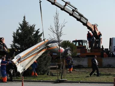 Alat berat dikerahkan untuk mengangkat puing helikopter yang hancur usai menabrak menara stasiun televisi, Turki, Jumat (10/3). Lima orang yang berada di dalamnya tewas seketika. (AP Photo)