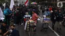 Pedangang menawarkan dagangannya kepada massa aksi saat demo penolakan omnibus law di kawasan patung kuda, Jakarta, Selasa (20/10/2020). Para pedagang kaki lima memanfaatkan moment aksi massa untuk mencari ke untungan meskupun sangat membahayakan bagi keselamatan mereka. (Liputan6.com/Angga Yuniar)