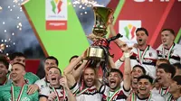Pemain Bologna merayakan kemenangan dengan mengangkat trofi Piala Italia (Coppa Italia) usai mengalahkan AC Milan pada laga final yang digelar di stadion Olimpico, Roma, pada 14 Mei 2025 waktu setempat atau pada Kamis (15/5/2025) dini hari WIB. (Isabella BONOTTO/AFP)
