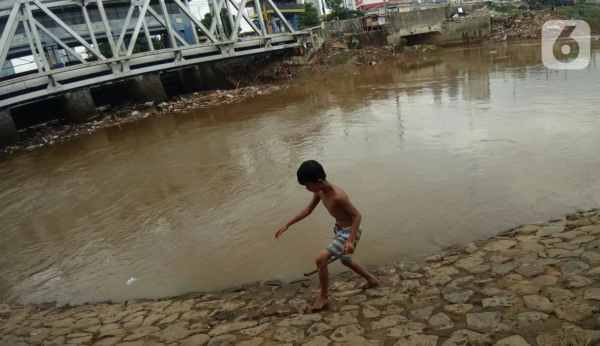 Seorang anak bermain di Bantaran sungai Kanal Banjir Barat, Tanah Abang, Jakarta, Sabtu (4/1/2020). Minimnya pengawasan  membuat anak-anak kerap bermain di tempat berbahaya yang berpotensi mengancam keselamatan mereka. (Liputan6.com/Angga Yuniar)