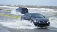 Mobil melewati banjir di sepanjang rute 90 saat jalur luar Badai Ida tiba di Gulfport, Miss (29/8/2021). (AP Photo/Steve Helber)