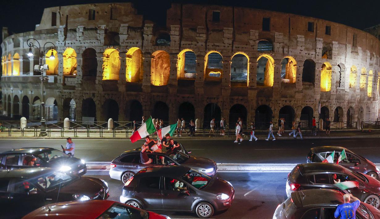Pendukung Italia merayakan kemenangan di depan Koloseum Kuno Roma, Italia pada Senin (12/07/2021), setelah Italia berhasil mengalahkan Inggris pada Final Euro 2020 yang berlangsung di Stadion Wembley. Italia mengalahkan Inggris 3-2 dalam adu penalti setelah bermain imbang 1-1. (AP/Riccardo De Luca)