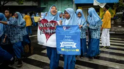 Sejumlah pelajar membawa spanduk saat menggelar demonstrasi menolak perayaan Hari Valentine di Surabaya, Jawa Timur, Kamis (14/2). Penolakan terjadi karena Valentine dinilai mempromosikan pergaulan bebas. (Juni Kriswanto/AFP)