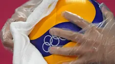 Petugas mengenakan sarung tangan plastik dan kain saat mendisinfeksi bola voli jelang pembukaan pertandingan voli Olimpiade Tokyo 2020 di Ariake Arena, Tokyo, Jepang, Jumat (23/7/2021). Olimpiade Tokyo 2020 digelar dengan penerapan protokol kesehatan ketat. (AP Photo/Frank Augstein)