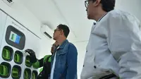 Mitra driver Gojek menjelaskan proses penukaran baterai motor listrik dengan konsep swap and go yang memakan waktu kurang dari 2 menit kepada Publik figur Andre Taulany (kanan), Surya Uji (tengah) di Bali. (Liputan6.com/HO)
