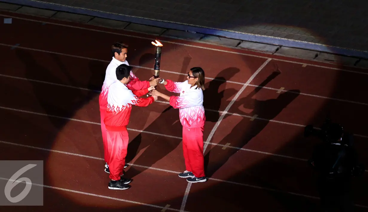 Liliyana Natsir (tengah) dan Tontowi Ahmad menyerahkan api PON XIX kepada Risa Suseanty saat upacara pembukaan di Stadion Gelora Bandung Lautan Api, Bandung, Sabtu (17/9). PON XIX Jabar berlangsung hingga 29 September. (Liputan6.com/Helmi Fithriansyah)