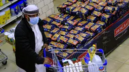 Seorang pria berbelanja bahan makanan dan persediaan saat mereka mempersiapkan diri seminggu menjelang bulan suci Ramadan di supermarket di ibu kota Yaman, Sanaa, Selasa (6/4/2021). (AFP Photo/Mohammed Huwais)