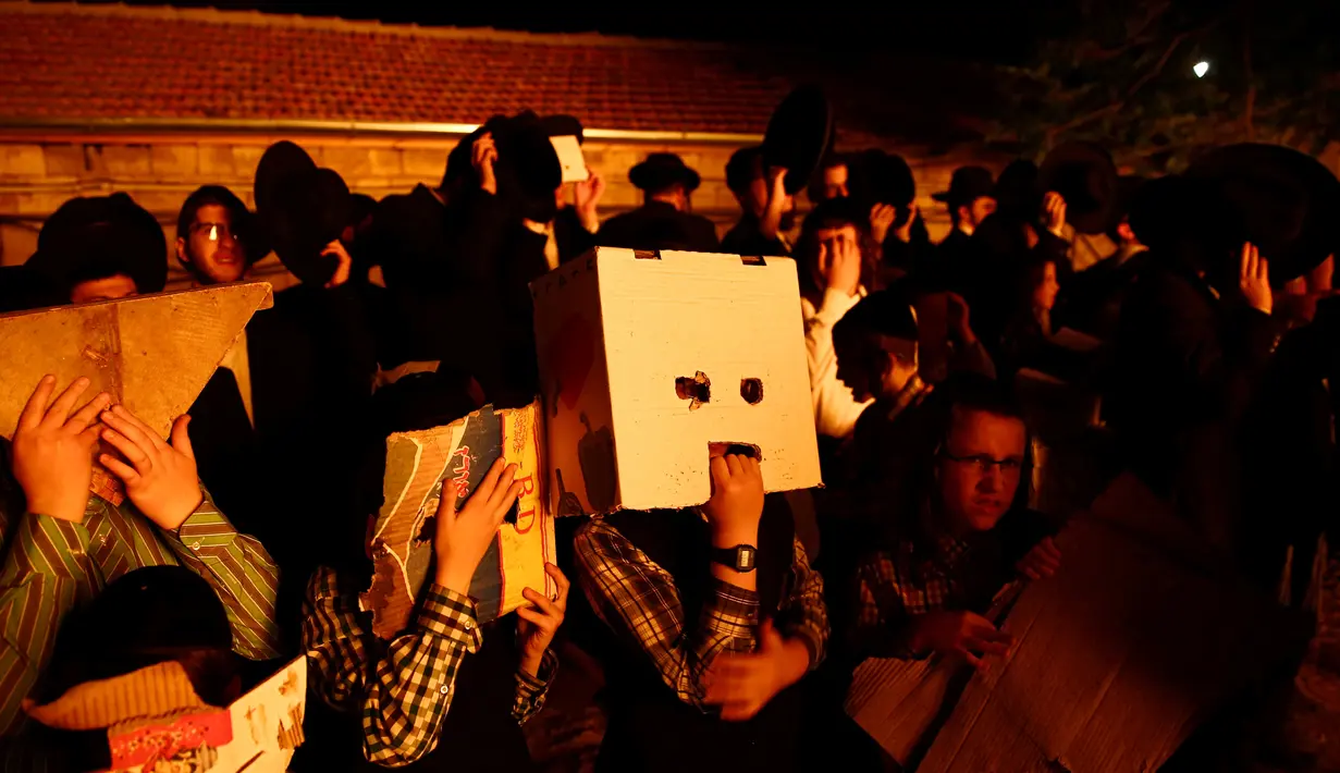 Warga Yahudi Ultra-Ortodoks melihat kobaran api unggun selama perayaan hari libur Yahudi Lag Ba-Omer di Shearim, Yerusalem, (25/5). Lag Ba-Omer merupakan hari libur Yahudi yang dirayakan pada hari ke-33 dari Penghitungan Omer. (REUTERS/Ronen Zvulun)