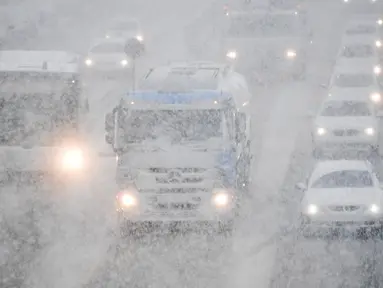 Sejumlah kendaraan melintas saat hujan salju turun di Munich, Jerman selatan, (18/4). Hujan salju yang melanda kawasan ini tidak menyurutkan warga untuk tetap beraktivitas. (AFP PHOTO / dpa / Tobias Hase / Jerman OUT)