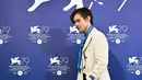 <p>Penyanyi dan aktor Inggris Harry Styles tiba untuk berpose selama sesi pemotretan untuk film "Don't Worry Darling" selama Venice Film Festival 2022 ke-79 di Venesia, Italia (5/9/2022). Harry Styles tampil mengenakan blazer krem bergaris-garis dengan celana panjang hitam longgar dan dasi biru. (AFP/Tiziana Fabi)</p>