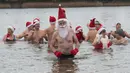 Anggota klub renang "Berliner Seehunde" (Berlin Seals) berendam di Danau Orankesee, Berlin, Minggu (25/12). Kegiatan yang sudah menjadi tradisi ini merupakan bagian dari perayaan tradisional Natal bagi warga Berlin. (Paul Zinken/dpa via AP)