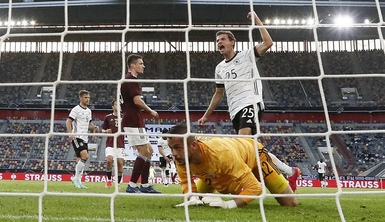 Penyerang timnas Jerman, Thomas Mueller berselebrasi setelah mencetak gol melewati kiper Latvia, Roberts Ozols dalam laga uji coba jelang EURO 2020 di Merkur Spiel Arena, Selasa (8/6/2021) dini hari WIB. Timnas Jerman memenangkan pertandingan dengan skor 7-1. (AP Photo/Martin Meissner)
