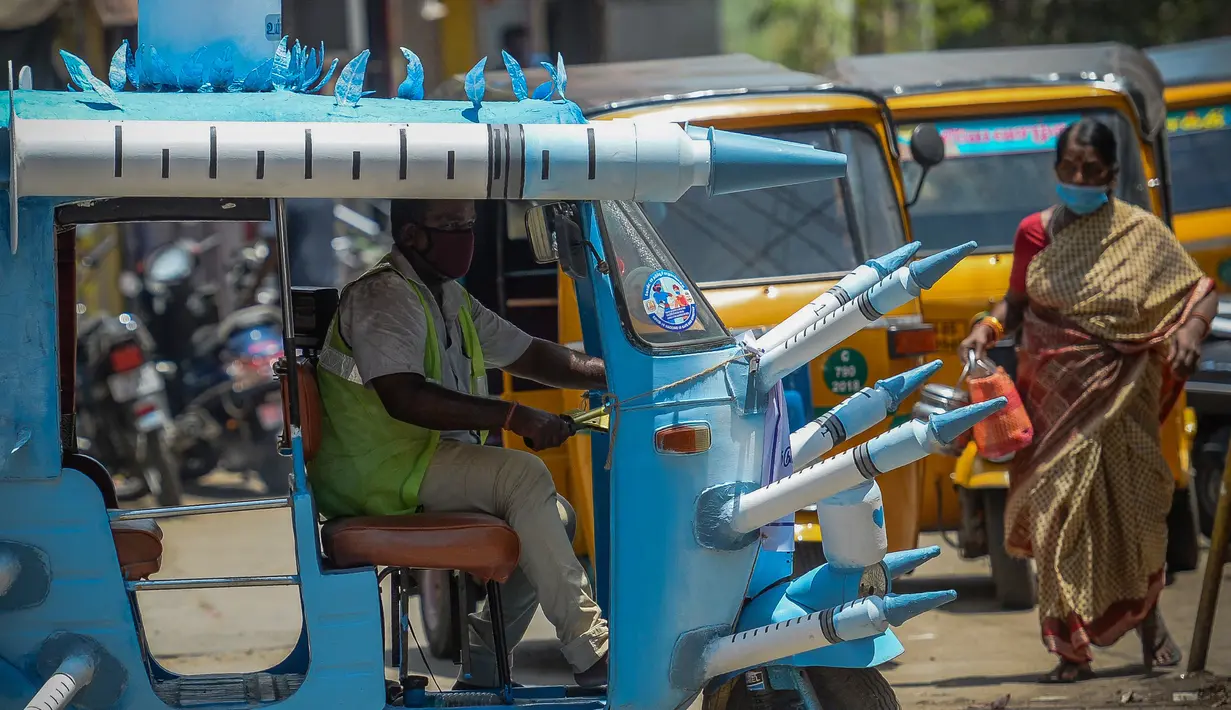 Seorang pekerja kota mengendarai bajaj yang dihiasi dengan jarum suntik tiruan di jalanan di Chennai, India pada Sabtu (3/6/2021). Seorang seniman di Chennai menghias bajaj tersebut untuk meningkatkan kesadaran orang-orang tentang pentingnya vaksinasi Covid-19. (Arun SANKAR/AFP)