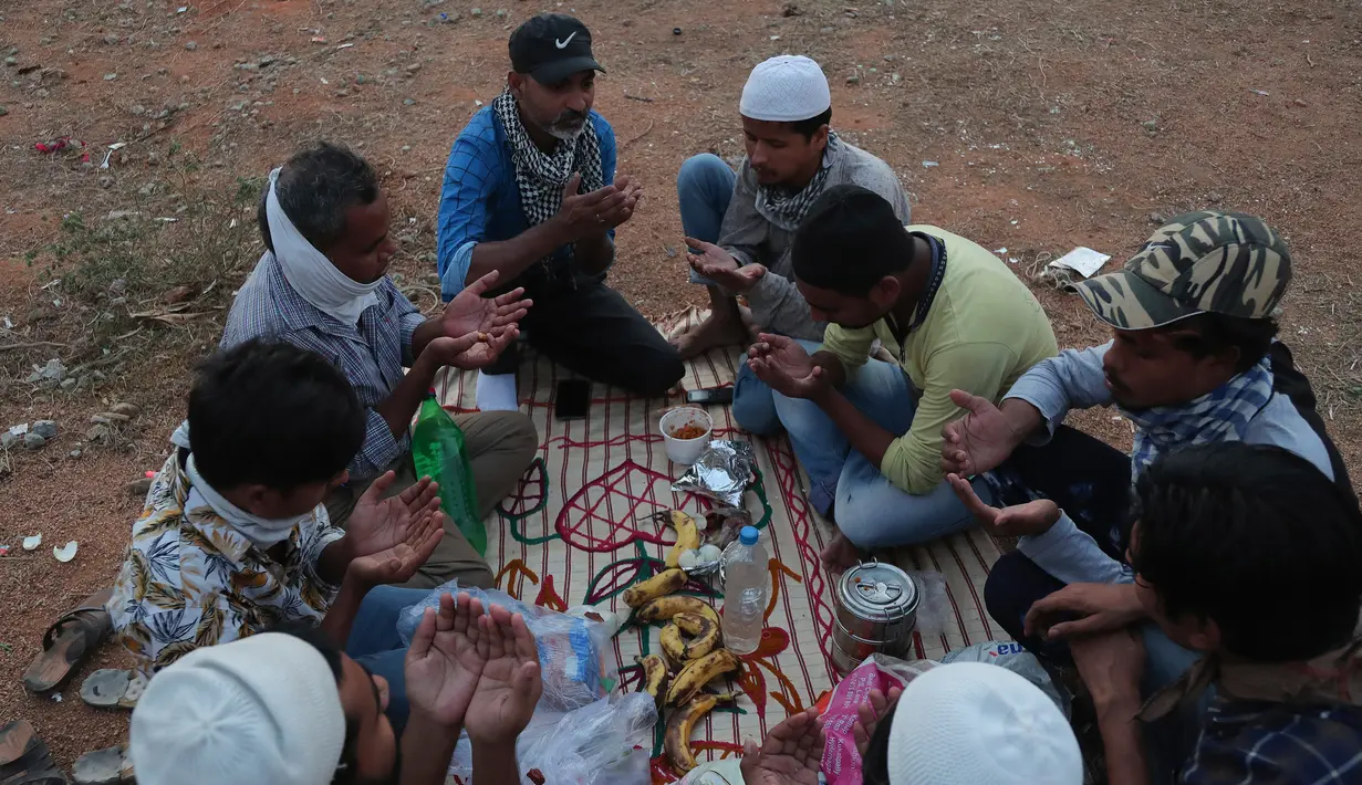 Buruh migran dari Uttar Pradesh berdoa sebelum berbuka puasa selama bulan Ramadan, saat bepergian untuk kembali ke negara asal mereka, selama lockdown untuk mencegah penyebaran Covid-19 di pinggiran Hyderabad, India, Selasa, (12/5/2020). (AP Photo/Mahesh Kumar A)