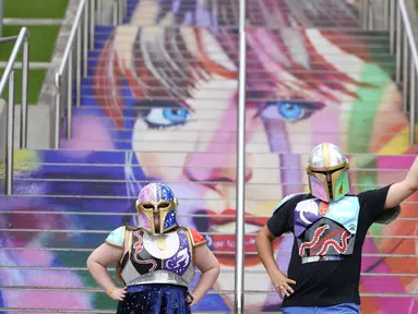 Kristina Broclebanl dan Max Avatar Barnett yang merupakan penggemar Taylor Swift berpose dengan potret Swift yang dilukis di tangga Stadion Wembley menjelang rangkaian konser The Eras Tour di London, Rabu (14/8/2024). (AP Photo/Alastair Grant)