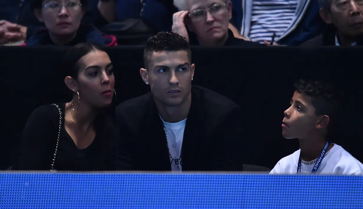 Cristiano Ronaldo bersama sang kekasih, Georgina Rodriguez dan anaknya, Cristiano Jr menyaksikan petenis Serbia, Novak Djokovic menghadapi John Isner dari AS pada laga tenis dunia, ATP Finals 2018, di O2 Arena, London, Senin (12/11). (Glyn KIRK/AFP)