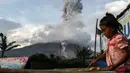 Seorang anak terlihat bermain saat gunung berapi Gunung Sinabung mengeluarkan abu vulkanik di Karo, Sumatra Utara (11/12). Gunung Sinabung kembali aktif pada tahun 2010 untuk pertama kalinya dalam 400 tahun. (AFP Photo/Ivan Damanik)