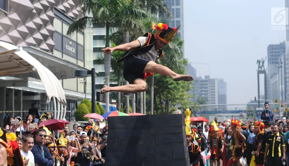 Salah satu pemuda peduli Nias melakukan atraksi lompat batu di kawasan Jalan Jenderal Sudirman, Jakarta, Minggu (4/3). Pemuda Peduli Nias melakukan beragam atraksi budaya untuk mempromosikan pariwisata di pulau tersebut. (Liputan6.com/Helmi Fithriansyah)