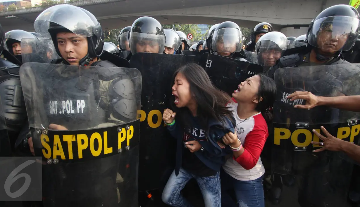 Dua remaja mencoba menghadang Satpol PP ketika eksekusi penggusuran bangunan di kawasan Rawajati, Pancoran, Jakarta, Kamis (1/9). Warga yang menolak penggusuran dan aparat saling beradu mulut hingga berujung bentrokan. (Liputan6.com/Immanuel Antonius)