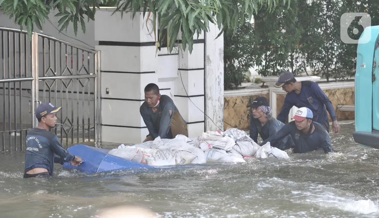 Petugas Sumber Daya Air (SDA) menggunakan perahu karet saat membawa karung pasir di Kompleks Perumahan Pantai Mutiara, Pluit, Jakarta, Minggu (7/6/2020). (Liputan6.com/Iqbal S. Nugroho)