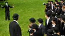 Seorang penggemar menirukan tingkah konyol Charlie Chaplin saat menggelar pertemuan di Corsier sur Vevey, Swiss, Minggu (16/4). Pertemuan yang dihadiri 662 orang itu dalam rangka merayakan HUT ke-128 Charlie Chaplin. (Laurent Gillieron/Keystone via AP)