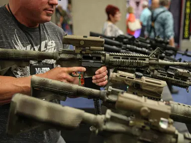 Seorang pria mencoba senjata api di aula pameran di Kay Bailey Hutchison Convention Center selama konvensi tahunan NRA, Texas (6/5). Konvensi tahunan NRA (National Rifle Association of America) ini menampilkan teknologi senjata. (AFP/Loren Elliot)