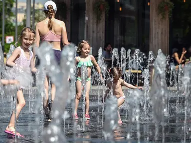 Orang-orang menikmati musim semi yang panas dengan mandi di air mancur di Moskow, Rusia, Selasa (18/5/2021). Suhu di Moskow telah mencapai 31 derajat Celcius. (Alexander NEMENOV/AFP)