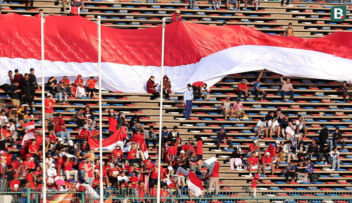 Pendukung Indonesia membentangkan bendera Merah Putih raksasa saat laga kedua Grup A Sepak Bola SEA Games 2023 antara Timnas Indonesia melawan Timnas Myanmar di Olympic Stadium, Phnom Penh, Kamboja, Kamis (04/05/2023). Skuad asuhan Indra Sjafri tersebut berhasil menang dengan skor telak 5-0. (Bola.com/Abdul Aziz)