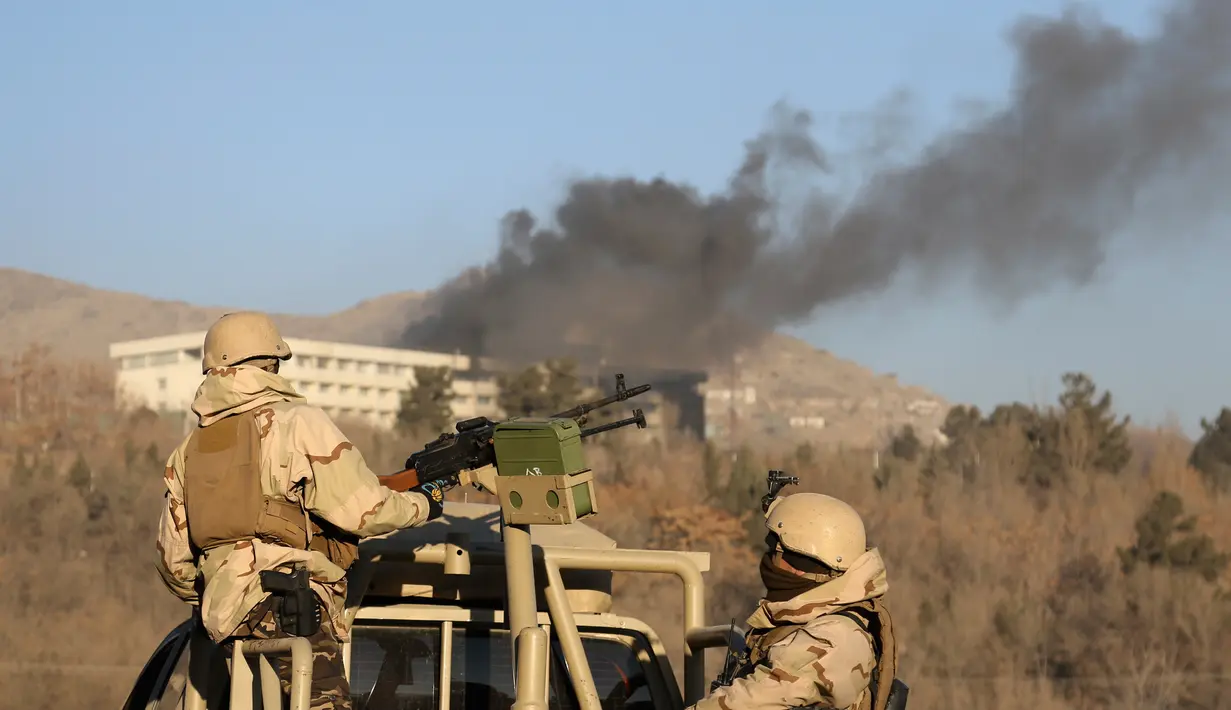 Pasukan keamanan Afghanistan berjaga saat asap keluar dari Hotel Intercontinental setelah terjadi serangan di Kabul, Afghanistan, Minggu (21/1). Orang-orang bersenjata menyerbu hotel mewah tersebut pada Sabtu, 20 Januari 2018 malam. (AP Photo/Rahmat Gul)