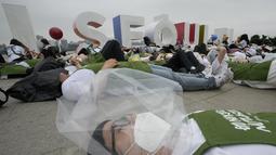 Aktivis lingkungan mengenakan pakaian yang terbuat dari sampah plastik berbaring di tanah selama kampanye untuk memperingati Hari Bumi melawan perubahan iklim di Seoul, Korea Selatan, Jumat (22/4/2022). (AP Photo/Ahn Young-joon)