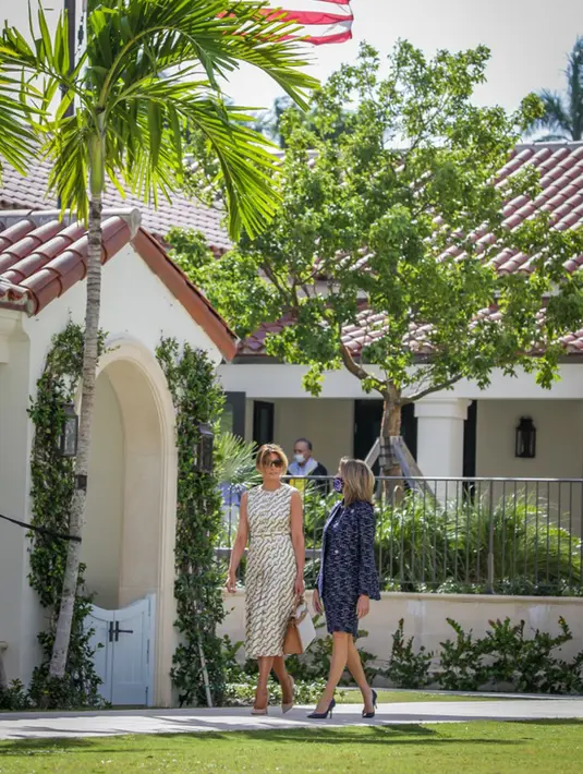 Ibu Negara Amerika Serikat Melania Trump (kiri) meninggalkan Morton and Barbara Mandel Recreation Center usai memberikan suara pada Pilpres AS di Palm Beach, Florida, 3 November 2020. Memakai outfit karya desainer, Melania memilih gaun midi tanpa lengan dengan garis leher tinggi. (Zak BENNETT/AFP)