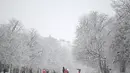 Orang-orang berjalan saat salju turun di Taman Retiro di pusat kota Madrid (7/1/2021). Sistem tekanan rendah bergerak ke timur laut dari Madeira di Atlantik, membawa massa udara yang sangat dingin ke Spanyol. (AFP/Gabriel Bouys)