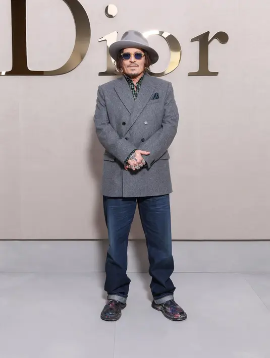 Johnny Depp terlihat menawan dengan double breasted abu-abu yang lapisi kemeja katun kotak-kotak. Lengkapi busananya, aktor senior itu kenakan celana jeans, topi lebar, dan pantofel yang estetik [Dior]