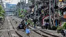 Pengendara motor melintas di bantaran rel kawasan pemukiman padat Pejompongan di tengah pandemi COVID-19, Jakarta, Kamis (28/1/2020). Sensus Penduduk 2020 (SP2020) mencatat penduduk DKI Jakarta pada bulan September 2020 sebanyak 10,56 juta  jiwa. (Liputan6.com/Johan Tallo)