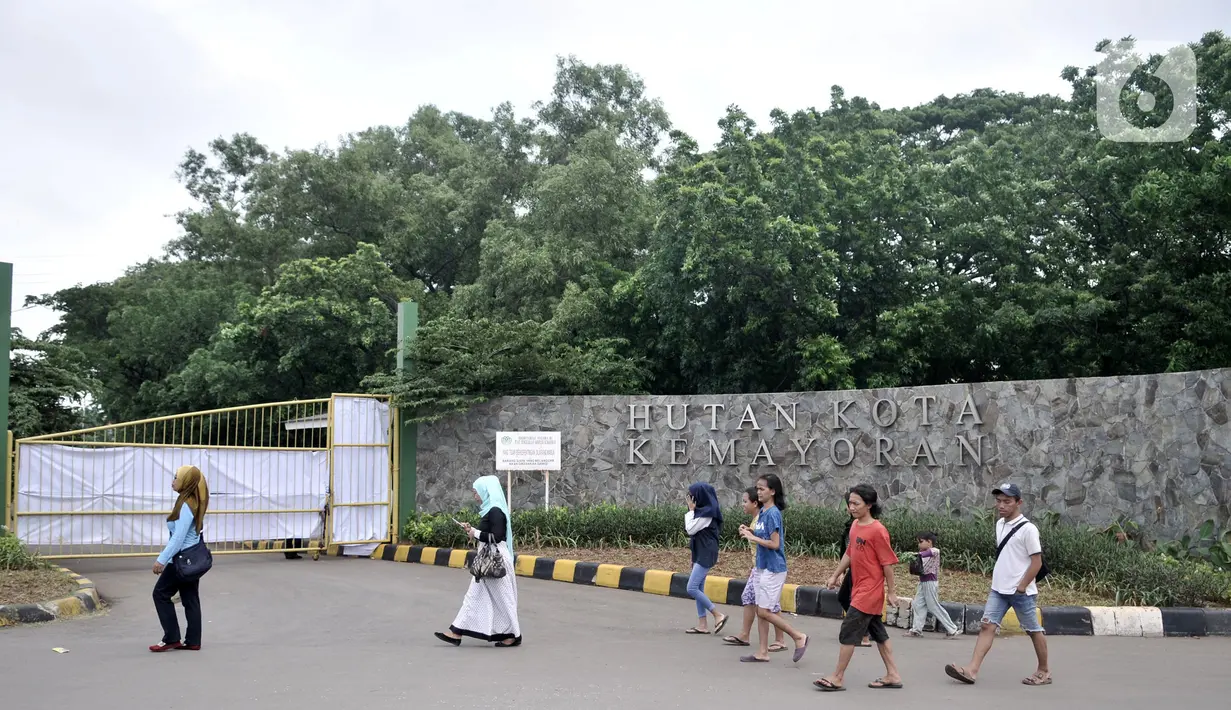 Warga melintas di depan pintu masuk Hutan Kota Kemayoran yang ditutup sementara, Jakarta, Minggu (22/12/2019). Beruntung tidak ada korban jiwa dalam kejadian tersebut, namun saat kejadian ada beberapa pekerja tengah melakukan finishing jembatan tercebur ke danau. (Merdeka.com/Iqbal S. Nugroho)