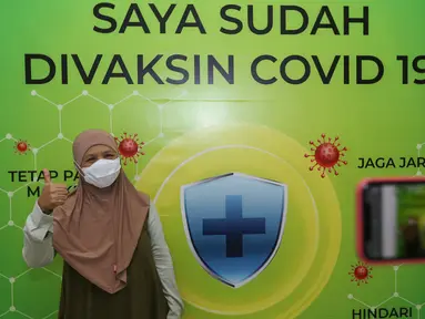 Warga Lansia foto dengan latar belakang Saya Sudah Divaksin Covid-19 di Cibubur Junction, Jakarta, Senin (22/03/2021). Warga lansia ber KTP DKI Jakarta atau yang tinggal di Jakarta Timur bisa menjalani vaksin mulai pukul 10.00 - 16.00 WIB hingga Sabtu 27 Maret. (Liputan6.com/Fery Pradolo)